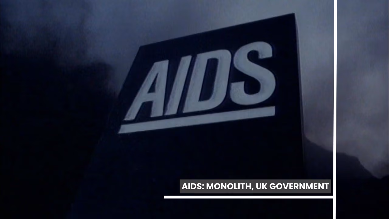 A frame from the UK government's AIDS campaign: a black stone monolith carved with the word AIDS, lit against fog and dark rock