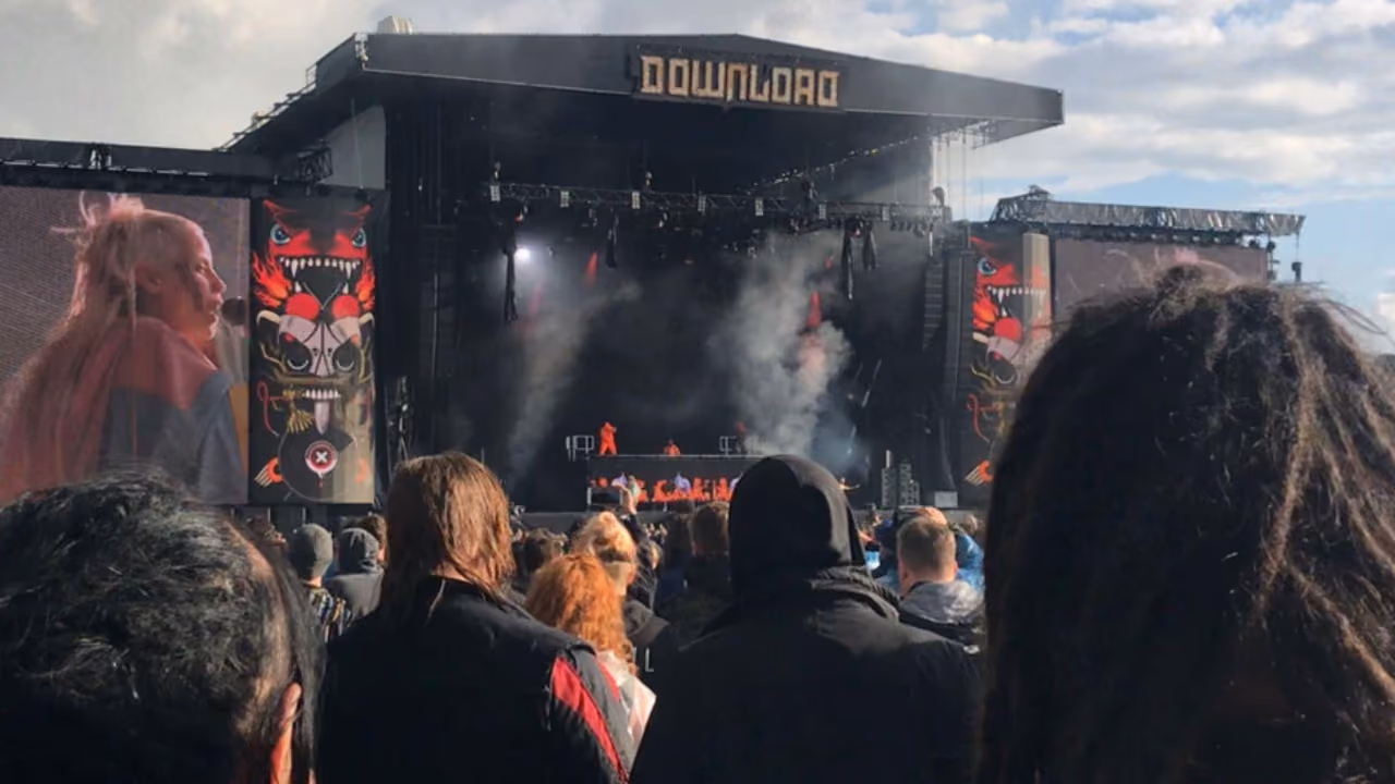 The main stage at Download Festival seen over the heads of the crowd, smoke drifting across it, a singer on the screen to the left