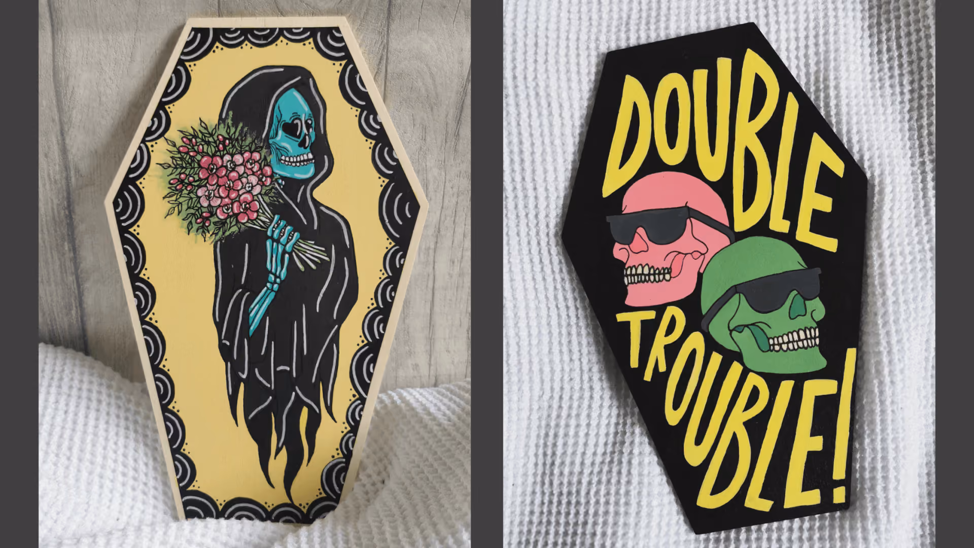 Two hand-painted coffin-shaped wooden plaques: one a hooded skeleton holding a bunch of pink flowers on yellow, the other black with two sunglasses-wearing skulls in pink and green under the words DOUBLE TROUBLE!