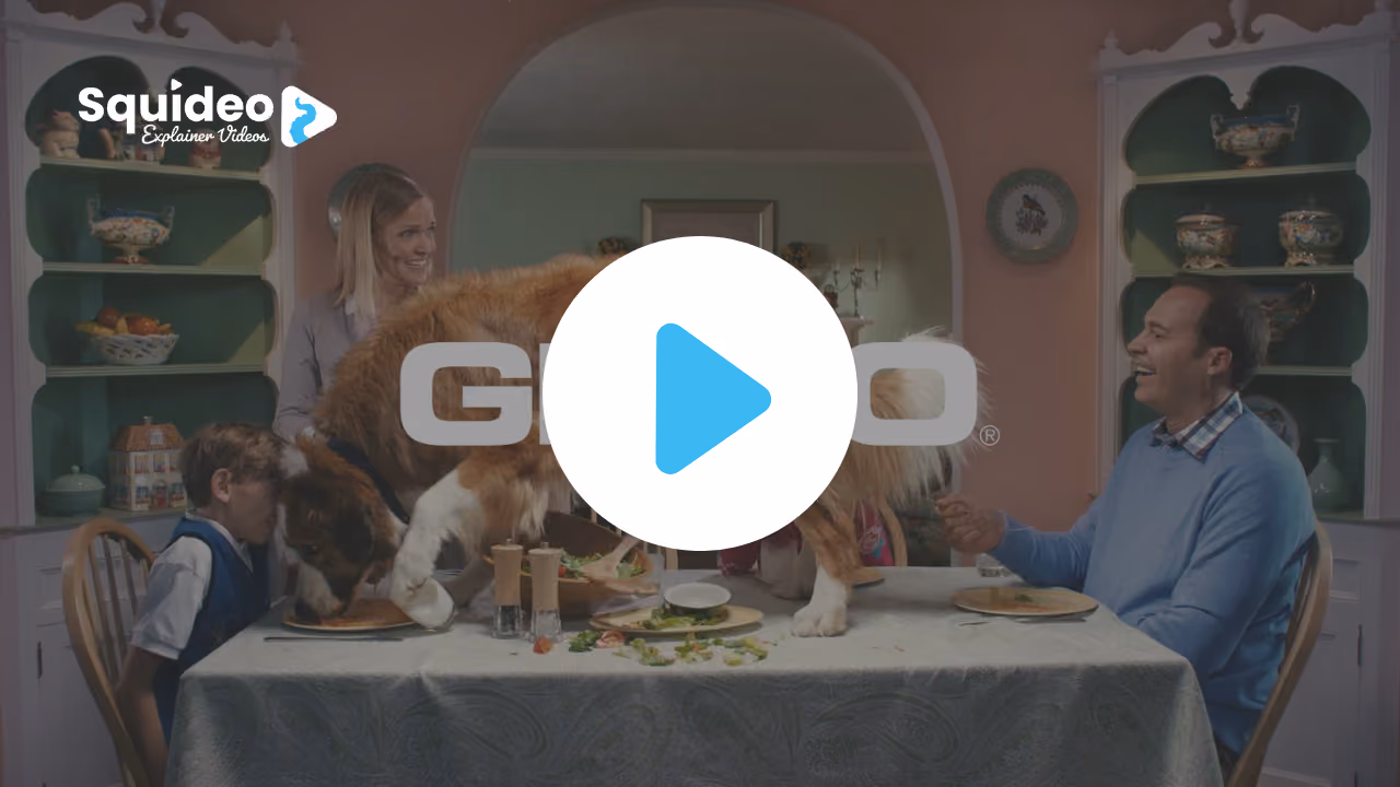 A St Bernard standing on the dinner table eating off a plate while the family look on, the Geico logo across the frame