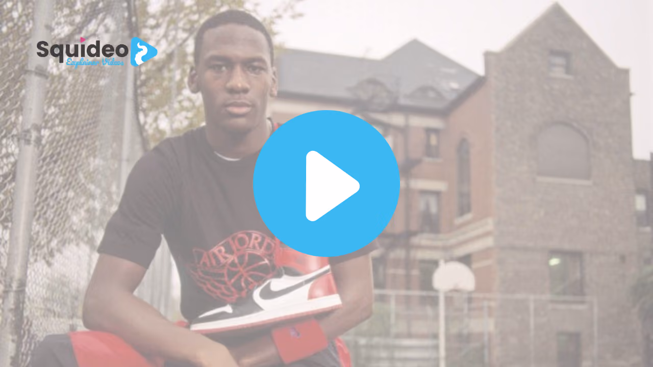 A young man sitting courtside in an Air Jordan t-shirt, holding a pair of black, white and red Air Jordan 1 trainers