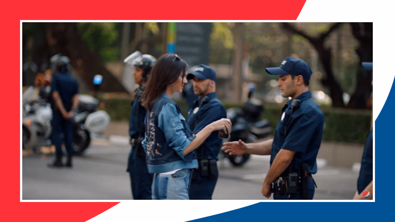 A still from Pepsi's 2017 advert: a young woman in a denim jacket offering a can of Pepsi to a line of police officers at a protest