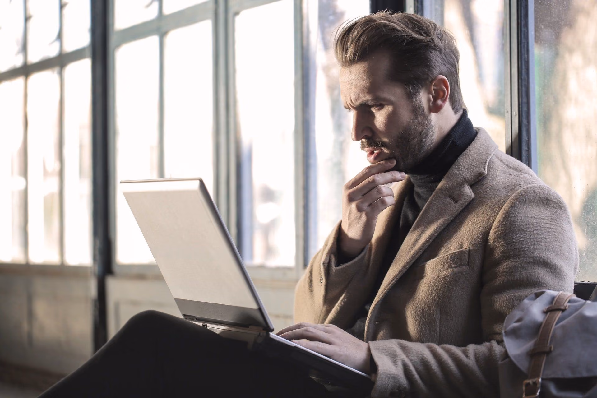 Confused Male Client Sitting Down, Looking at Laptop